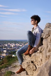 Photo of Travel blogger in sunglasses on stone looking at beautiful view outdoors