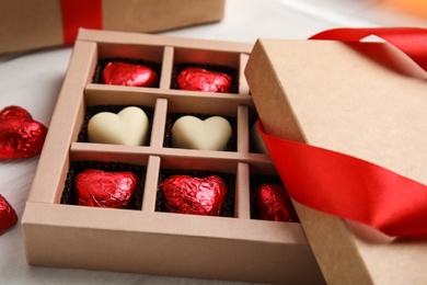 Photo of Tasty heart shaped chocolate candies on white wooden table, closeup. Happy Valentine's day