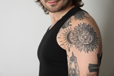 Photo of Young man with tattoos on body against white background, closeup