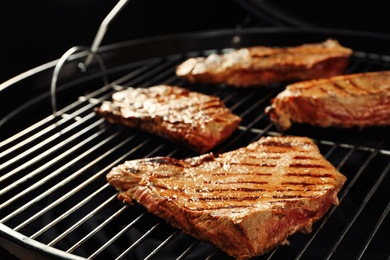 Photo of Fresh grilled tasty meat steaks on barbecue grate