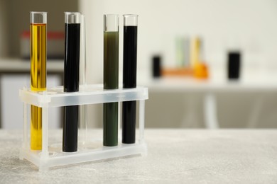 Photo of Test tubes with different types of crude oil on light grey table, space for text
