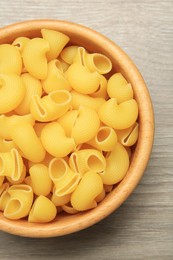 Photo of Raw macaroni pasta in bowl on light grey wooden table, top view