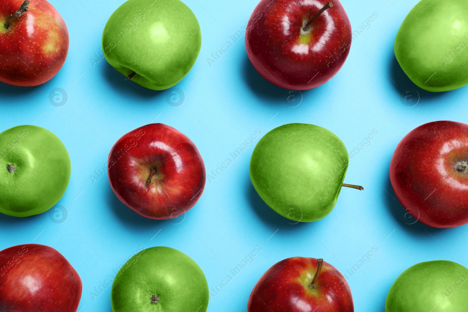 Photo of Tasty ripe apples on light blue background, flat lay