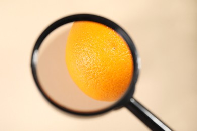 Photo of Cellulite problem. Magnifying glass over orange on beige background, top view