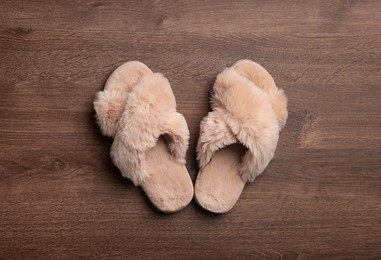 Photo of Pair of soft slippers on wooden floor, top view