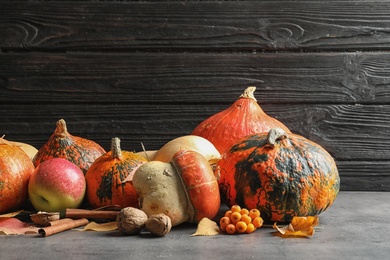 Photo of Composition with different pumpkins on table against dark wall. Autumn holidays