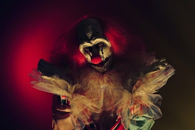 Photo of Terrifying clown in darkness. Halloween party costume