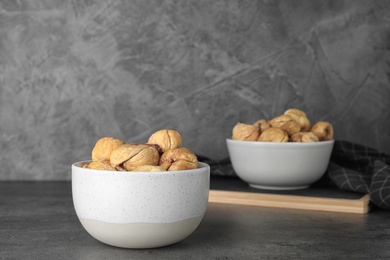 Photo of Bowl with dried figs on grey table, space for text. Healthy fruit