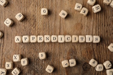 Photo of Word Appendicitis made of cubes with letters on wooden table, flat lay