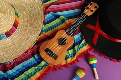 Photo of Flat lay composition with Mexican sombrero and black Flamenco hats, ukulele and maracas on purple table