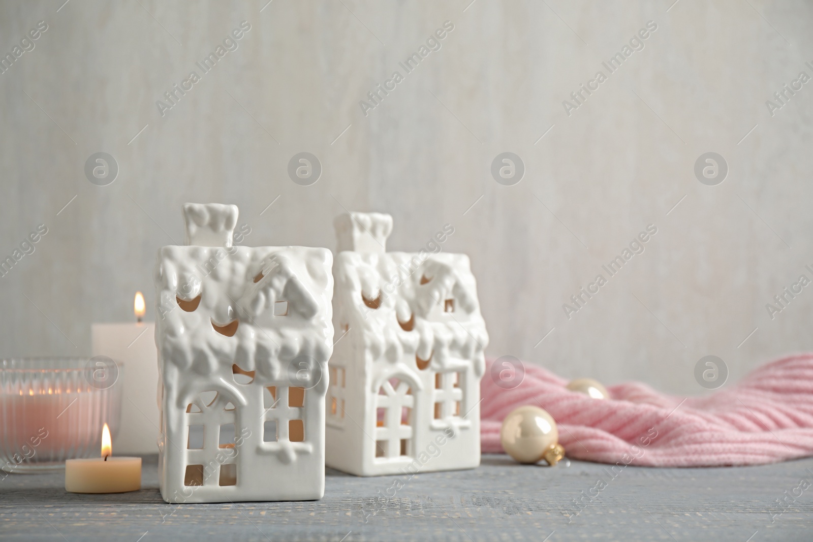 Photo of Composition with house shaped candle holders on grey wooden table, space for text. Christmas decoration