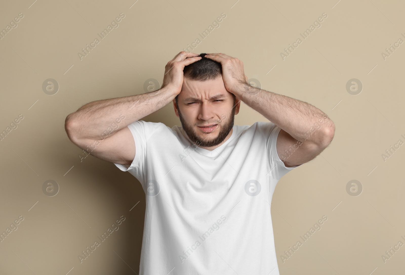 Photo of Man suffering from headache on beige background