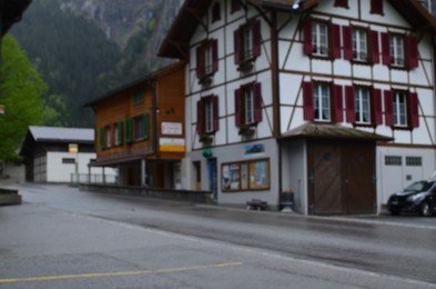 Blurred view of houses near empty asphalt road in mountains