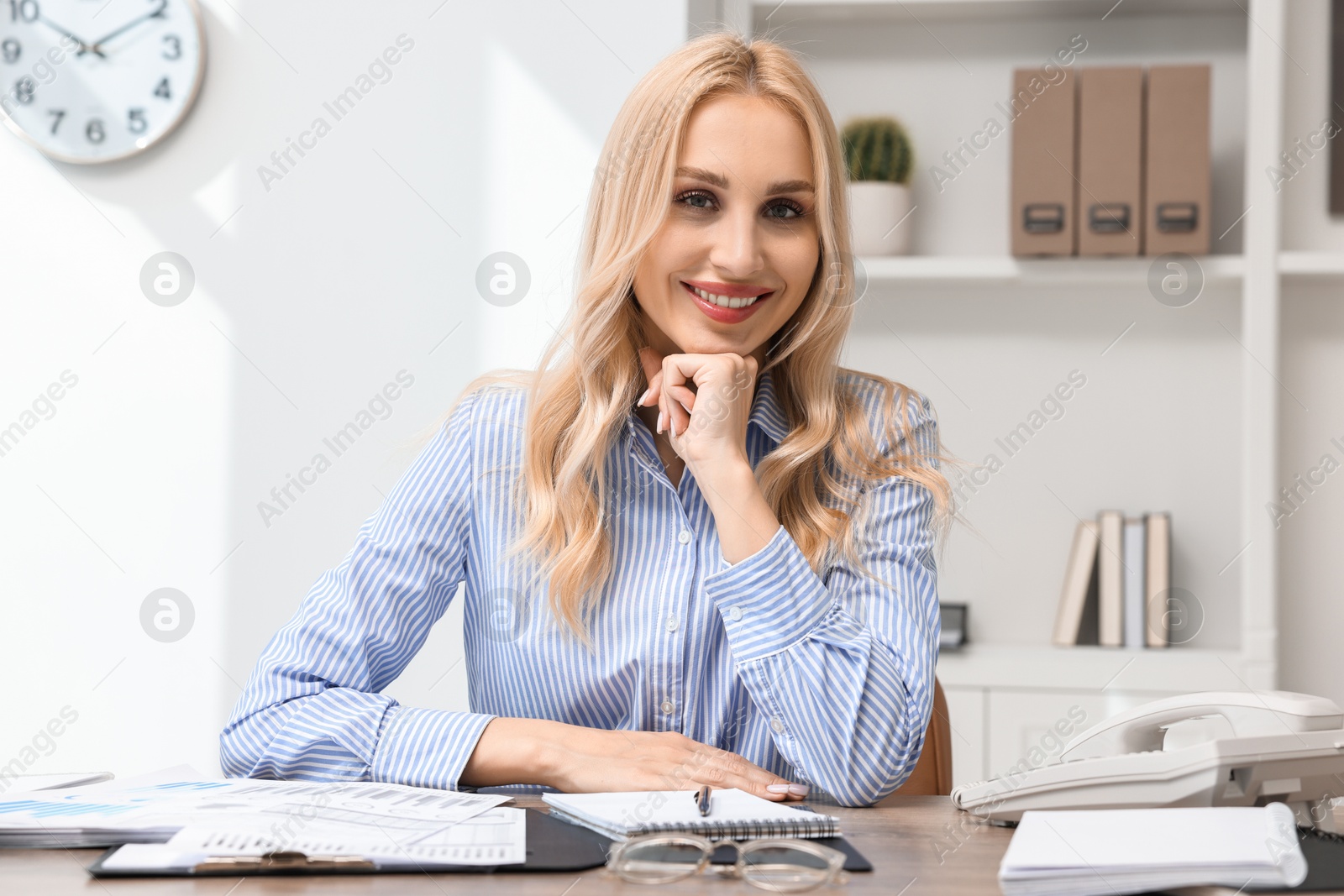 Photo of Happy secretary at table with stationery in office