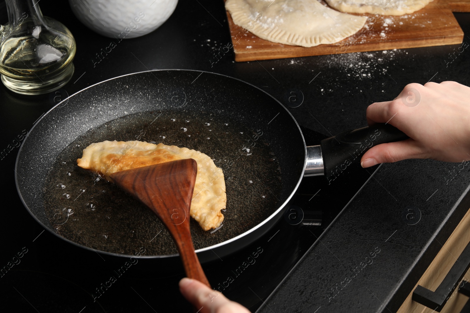 Photo of Woman cooking chebureki in frying pan, closeup