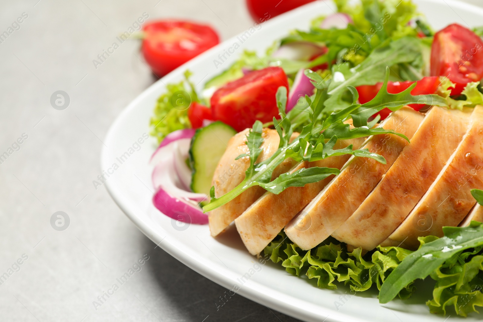 Photo of Delicious salad with meat, arugula and vegetables on grey table, closeup