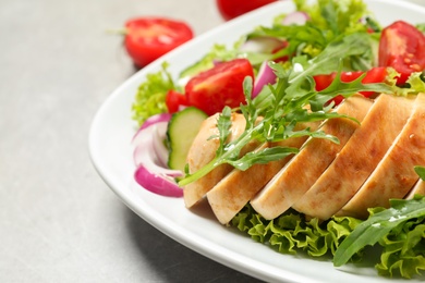 Photo of Delicious salad with meat, arugula and vegetables on grey table, closeup