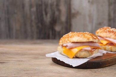 Photo of Delicious bagels with ham and cheese on wooden table, space for text