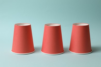 Photo of Three red cups on light blue background. Thimblerig game