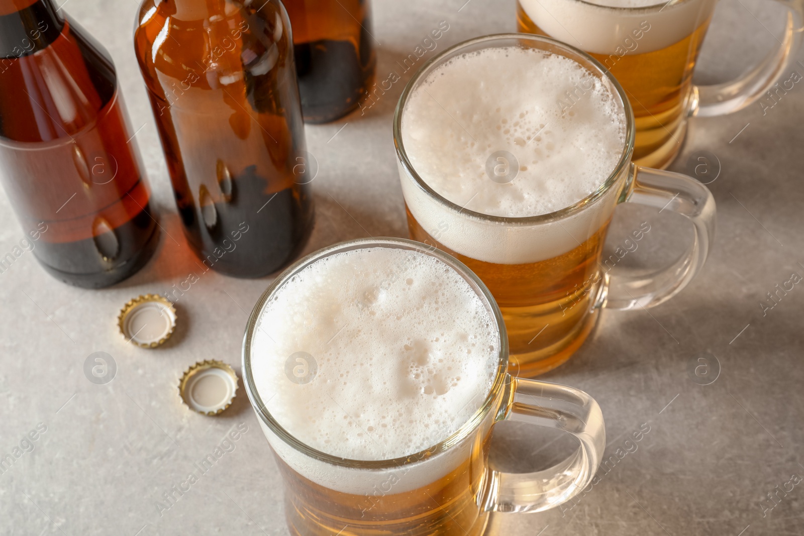 Photo of Glass mugs and bottles of cold tasty beer on table