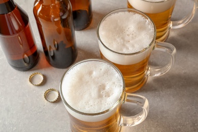 Glass mugs and bottles of cold tasty beer on table