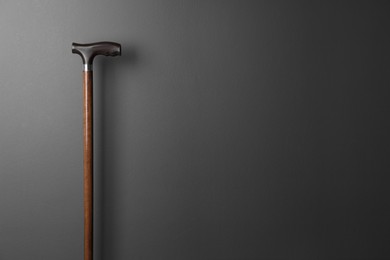 Elegant walking cane on grey background. Space for text