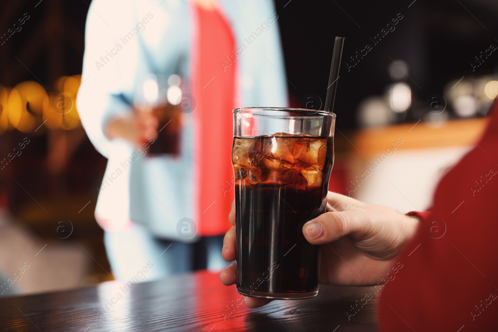 Photo of Man holding glass of cola at table in bar, closeup. Space for text