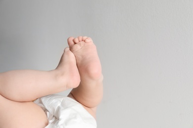 Photo of Cute little baby against light background, closeup on feet. Space for text
