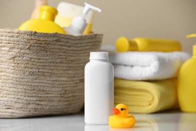 Photo of Bottles of baby cosmetic products, rubber duck and towels on white table.