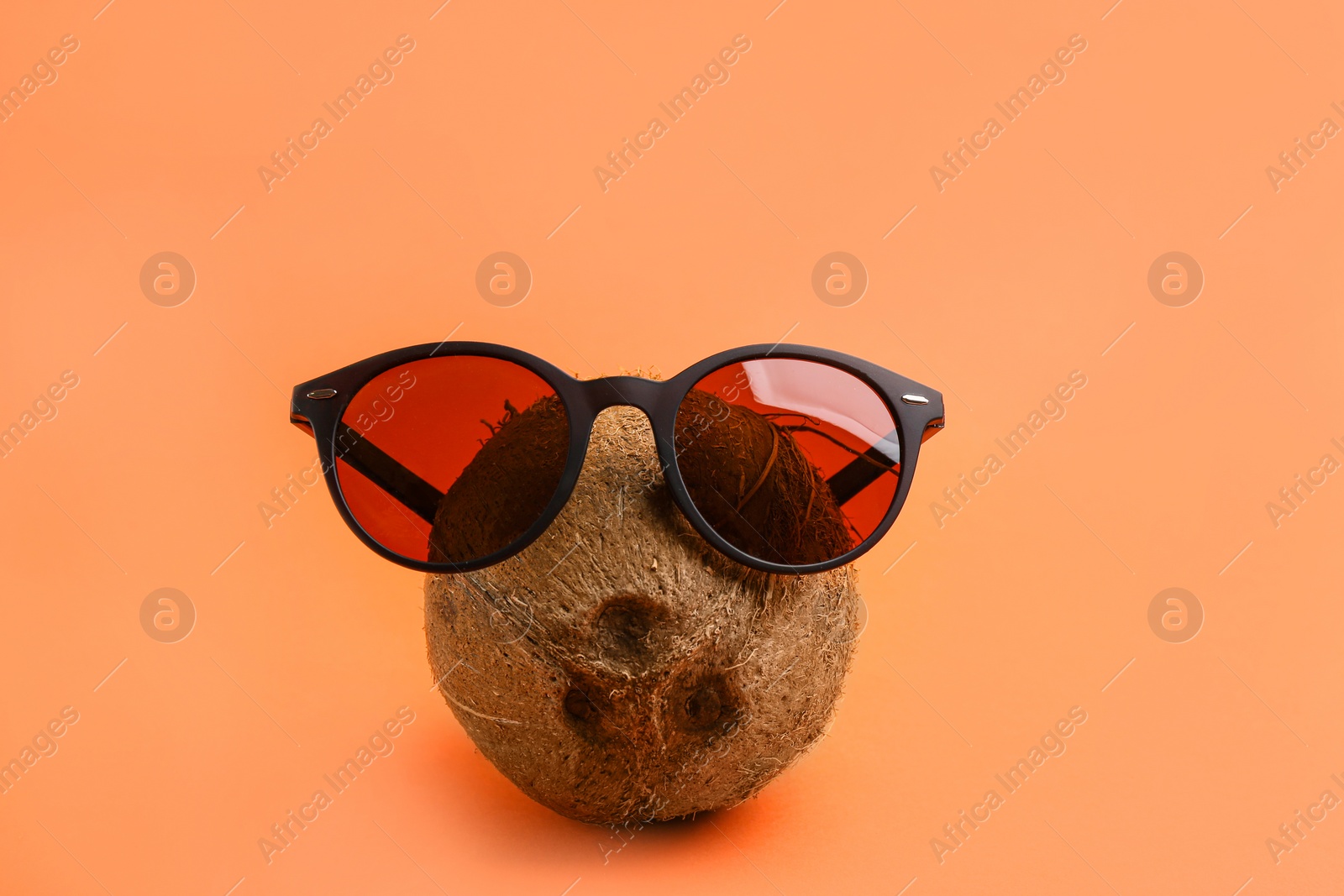 Photo of Funny face made of coconut and sunglasses on coral background. Vacation time