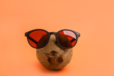 Funny face made of coconut and sunglasses on coral background. Vacation time
