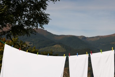 Photo of Laundry with clothes pins on line outdoors. Space for text