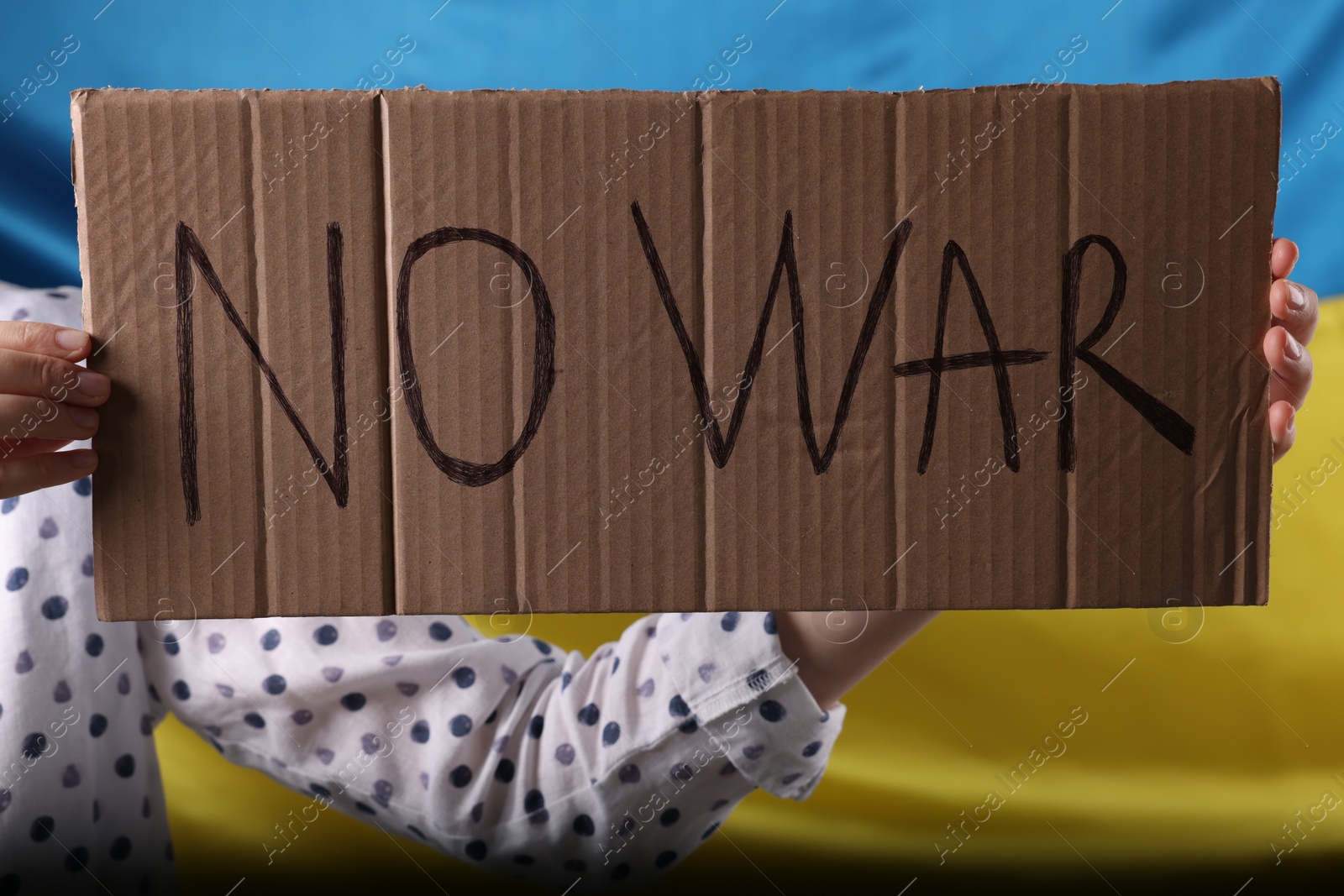 Photo of Woman holding poster with words No War near Ukrainian flag, closeup