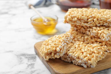 Photo of Delicious rice crispy treats on white marble table, closeup. Space for text