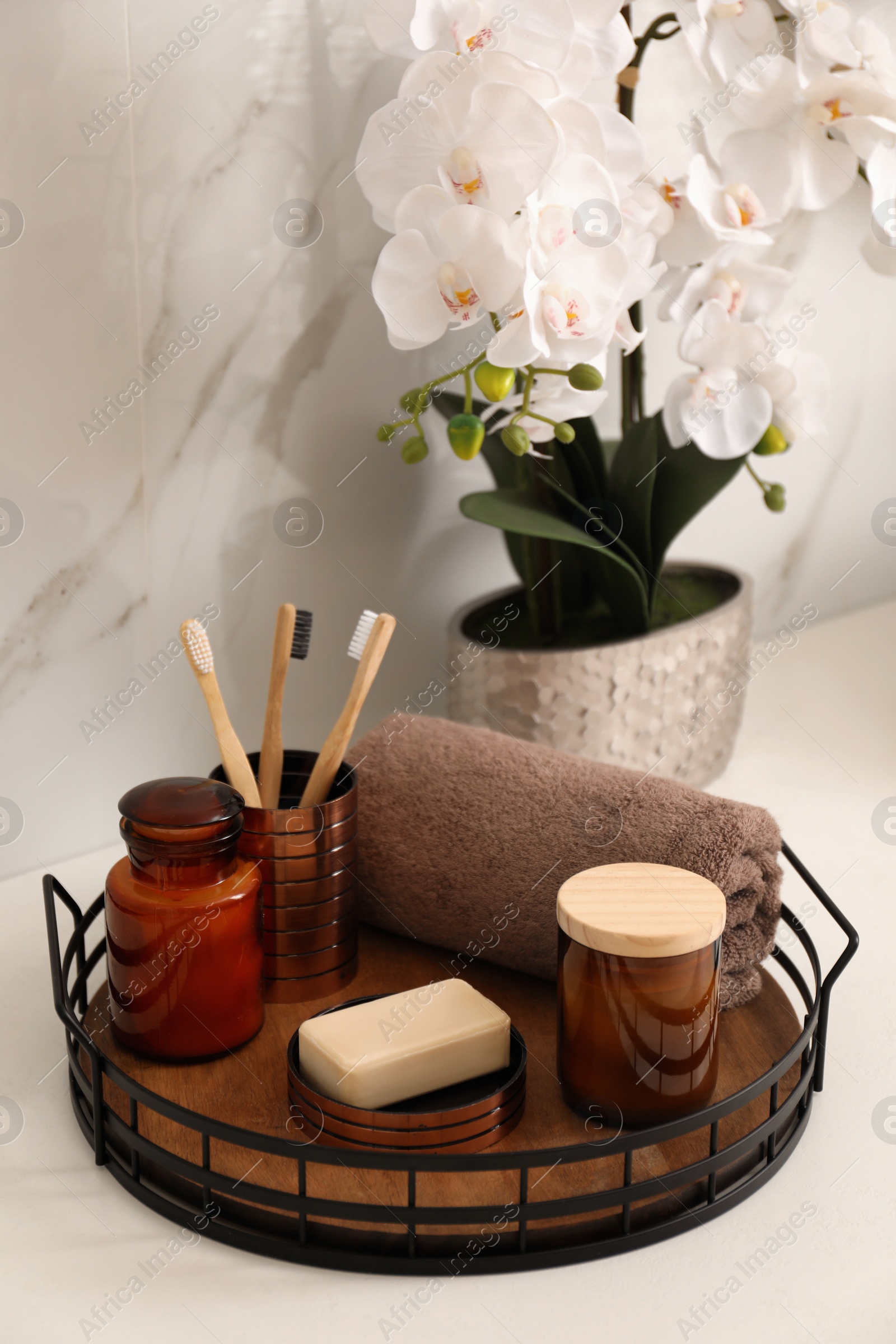 Photo of Beautiful flowers and different toiletries on countertop in bathroom