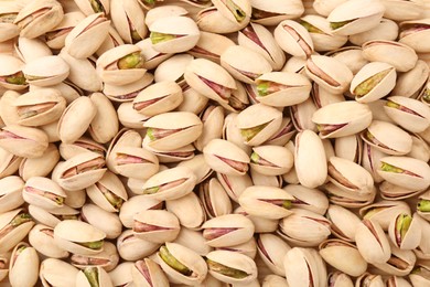 Tasty unpeeled pistachios as background, top view