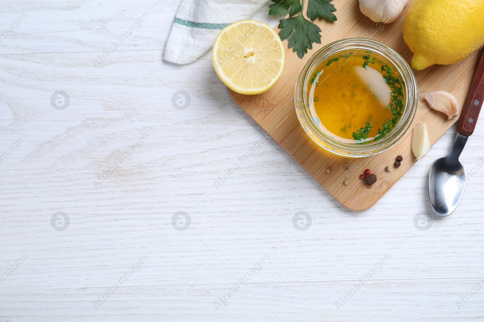 Photo of Jar of lemon sauce and ingredients on white wooden table, flat lay with space for text. Delicious salad dressing