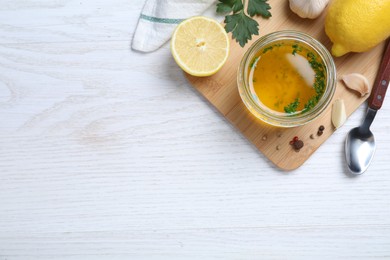 Jar of lemon sauce and ingredients on white wooden table, flat lay with space for text. Delicious salad dressing