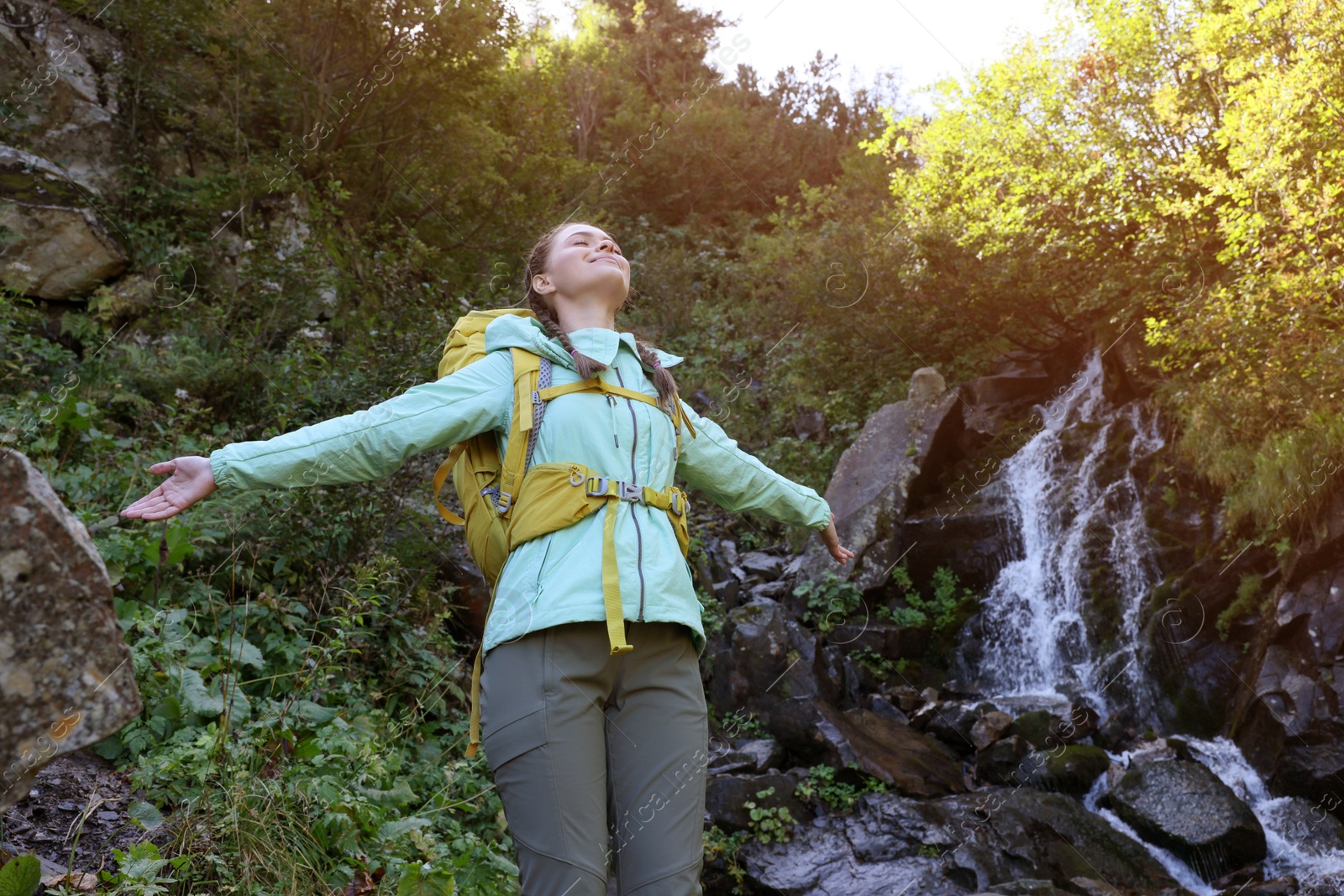 Photo of Tourist with backpack near waterfall in mountains