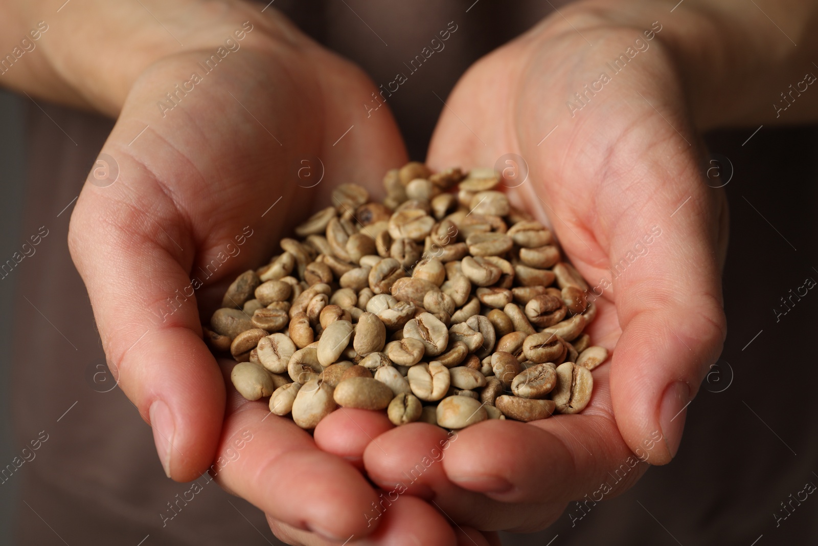 Photo of Woman holding pile of green coffee beans, closeup