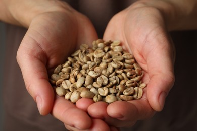 Photo of Woman holding pile of green coffee beans, closeup