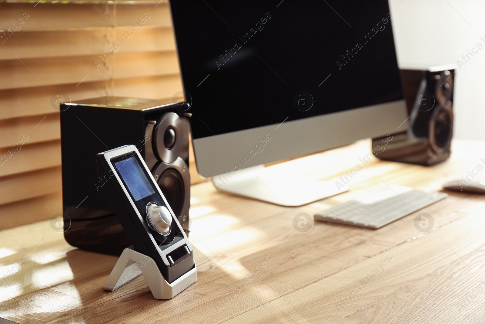 Photo of Modern computer with audio speakers and remote on table indoors