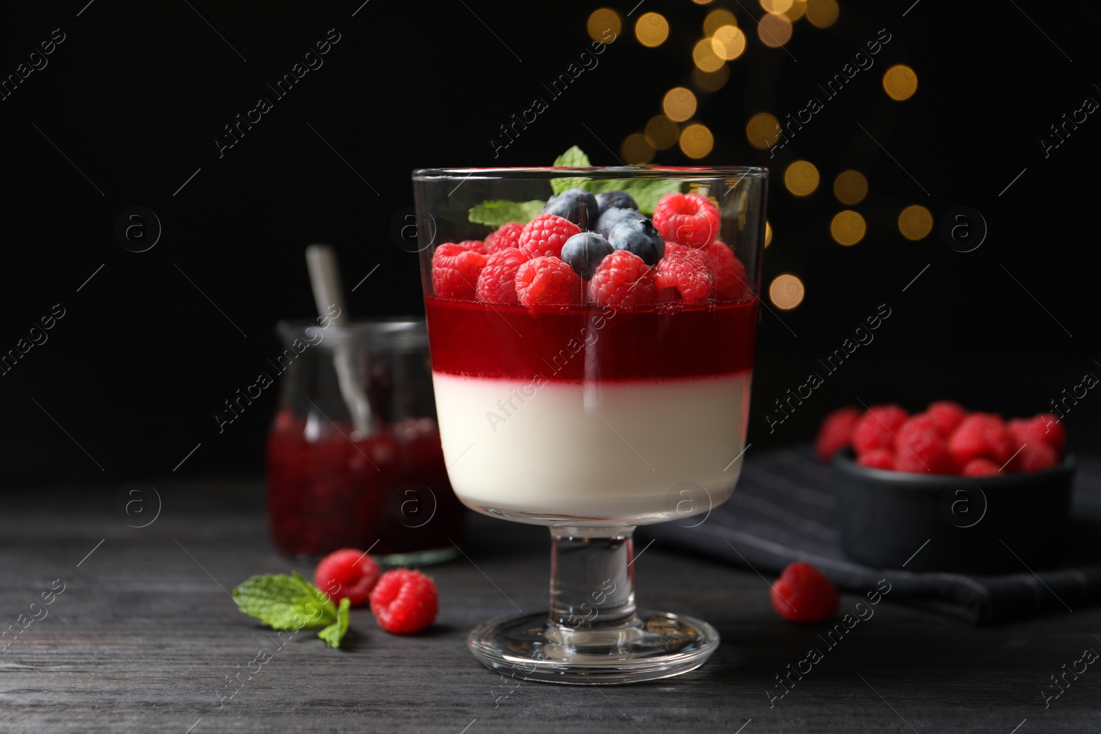 Photo of Delicious panna cotta with berries on black wooden table