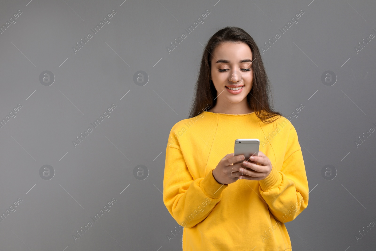 Photo of Young woman using phone against color background