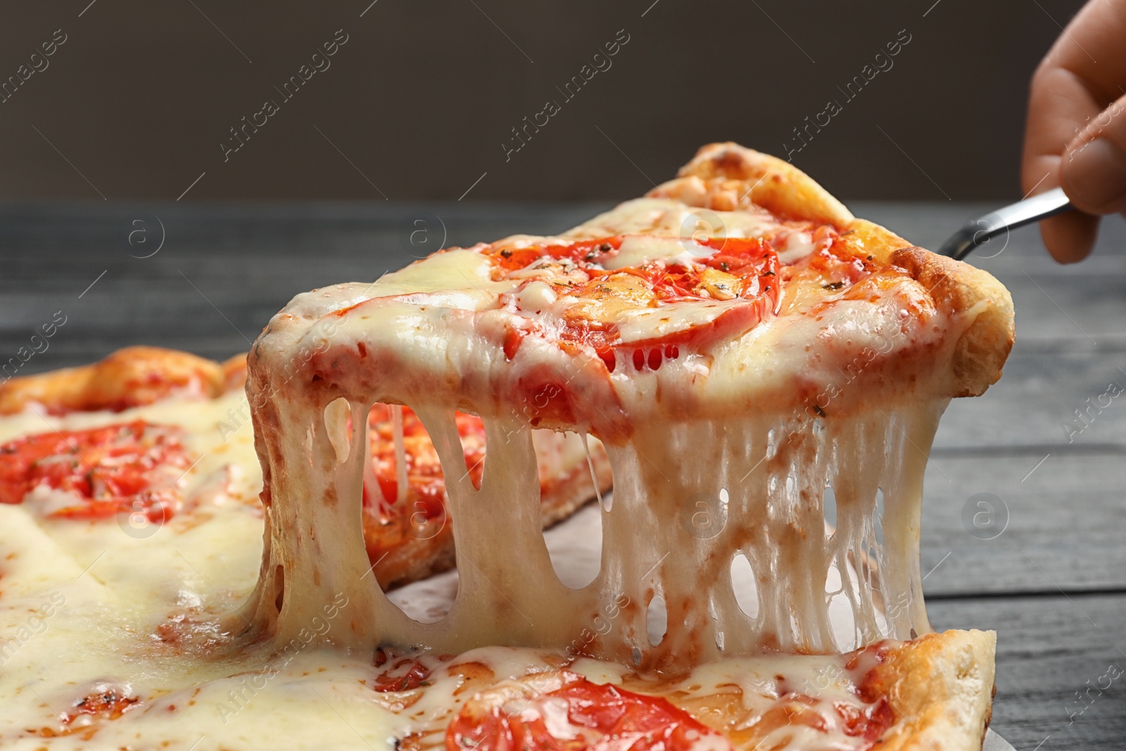 Photo of Woman taking slice of hot cheese pizza Margherita on table, closeup