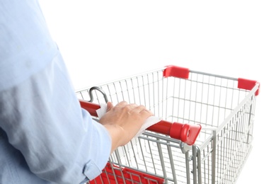 Photo of Woman holding shopping cart handle with tissue paper on white background, closeup
