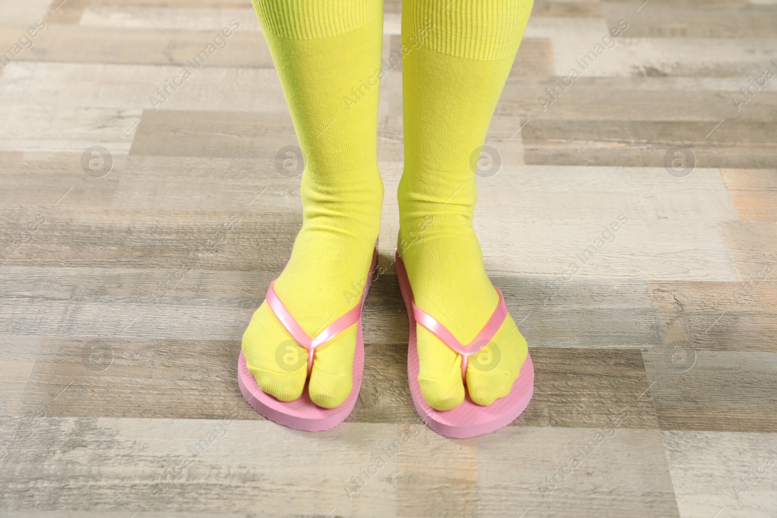 Photo of Woman wearing bright socks with flip-flops standing on floor
