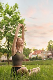 Teenage girl doing morning exercise on green grass in park