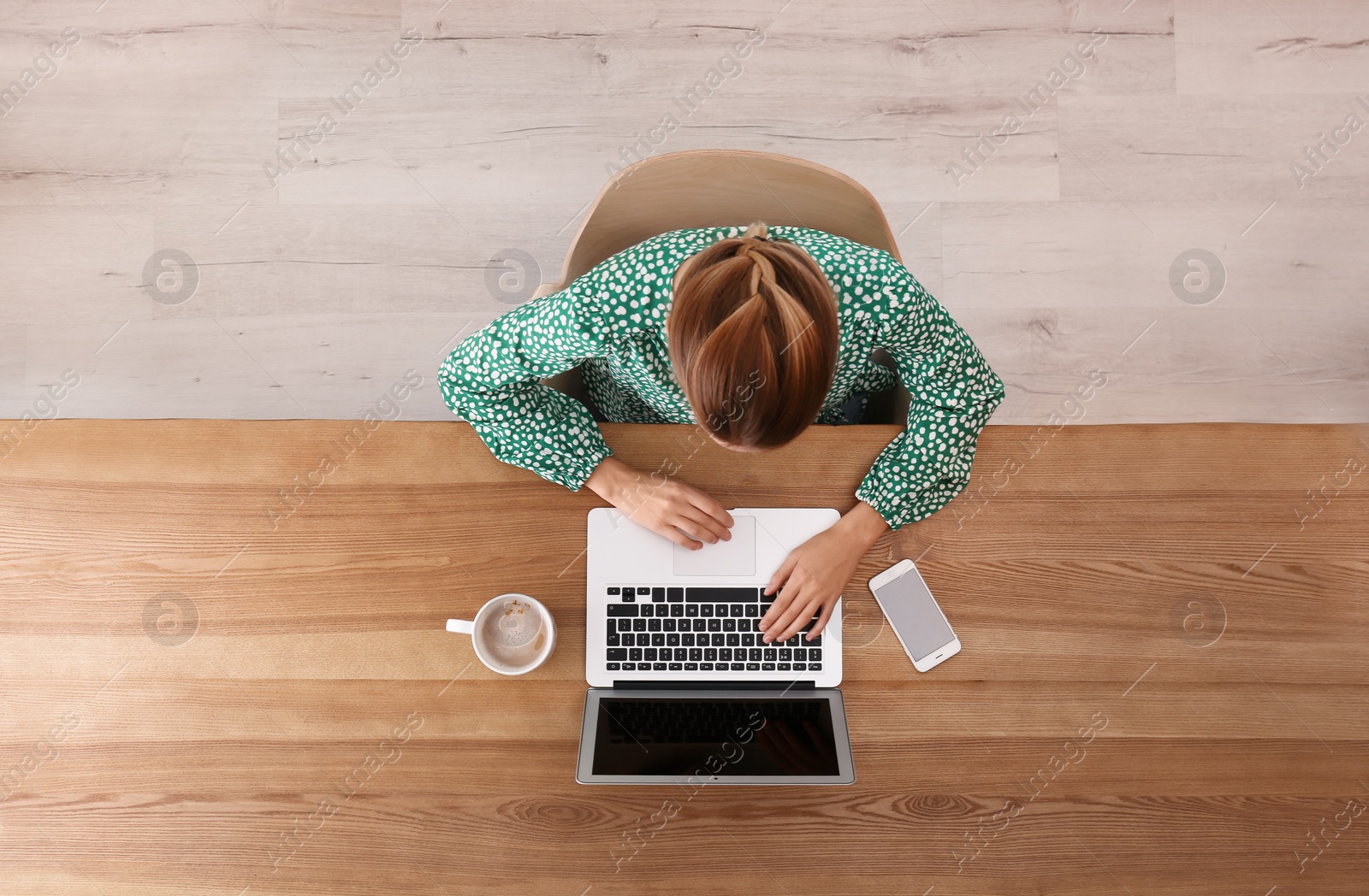 Photo of Woman working with laptop at table indoors, top view