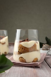 Photo of Delicious tiramisu with coffee beans in glasses on wooden table